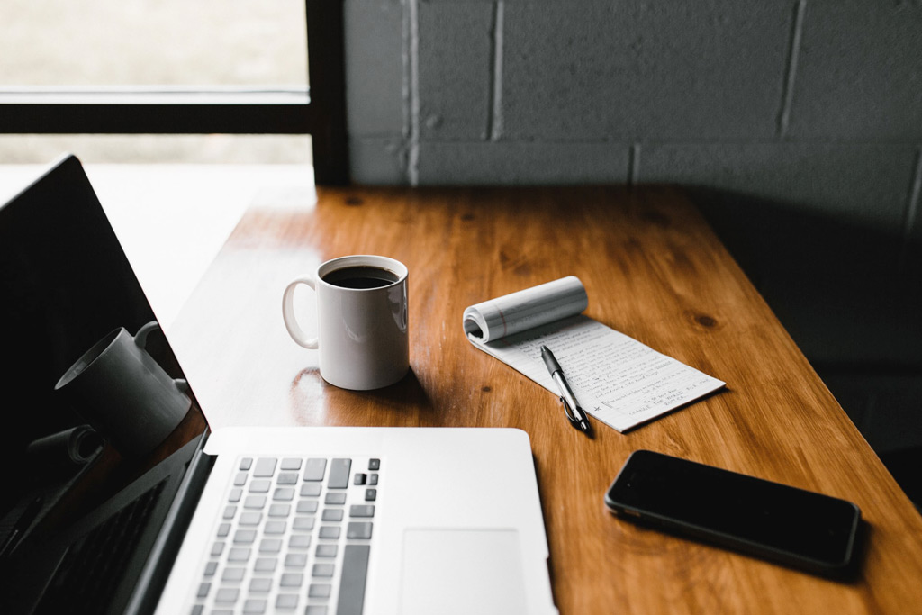 Laptop, coffee, notepad and mobile phone on a desk